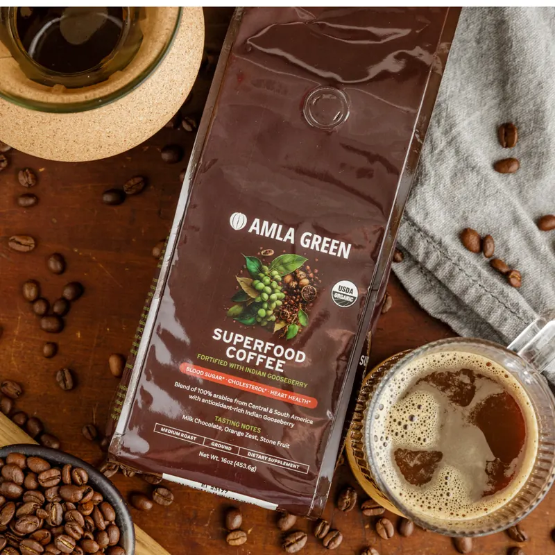 Bag of Amla Green Superfood Coffee on a wooden table with coffee beans and a fresh cup