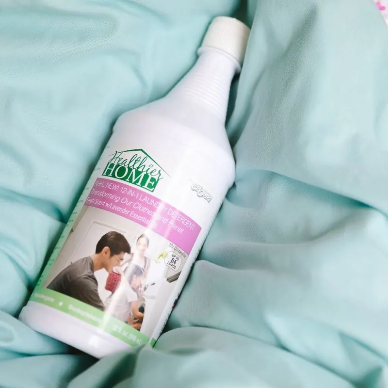 Bottle of Healthier Home cleaner lying on rumpled light blue bedding